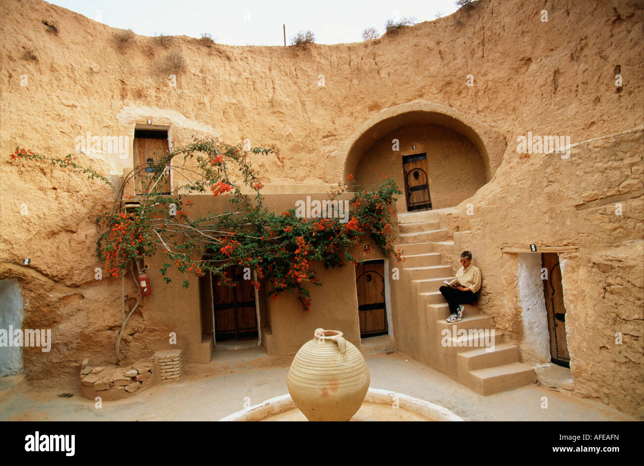 Tunisia Matmata, Sahara Desert, Tourist sitting on stairs of cave which is being used as hotel, before as house Stock Photo