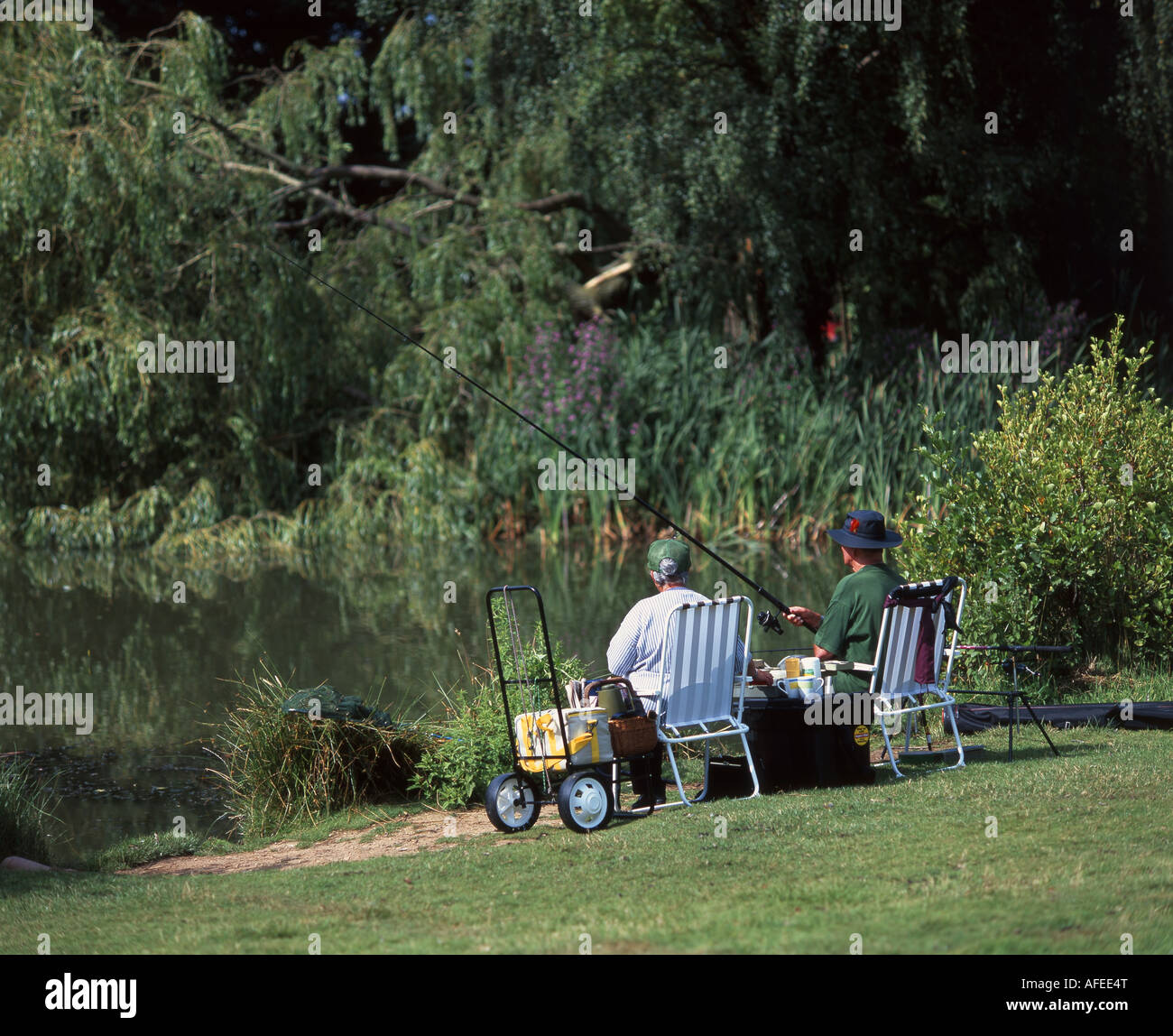 Older couple fishing in small fresh water lake, Stanwell Moor, Surrey, England, United Kingdom Stock Photo