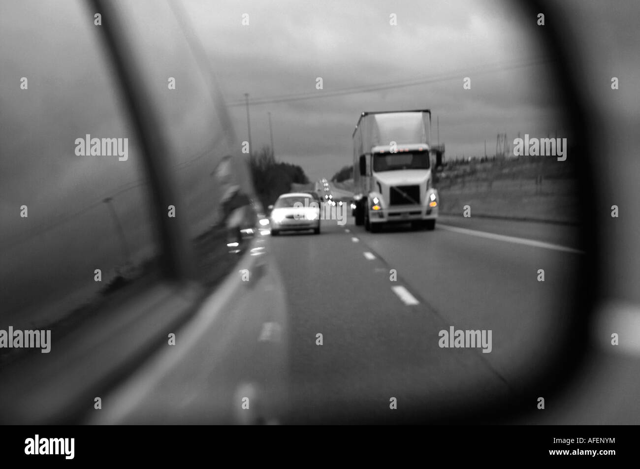 Cars and trucks in traffic on a United States Interstate Highway seen in a rear view mirror in mostly black and white Stock Photo