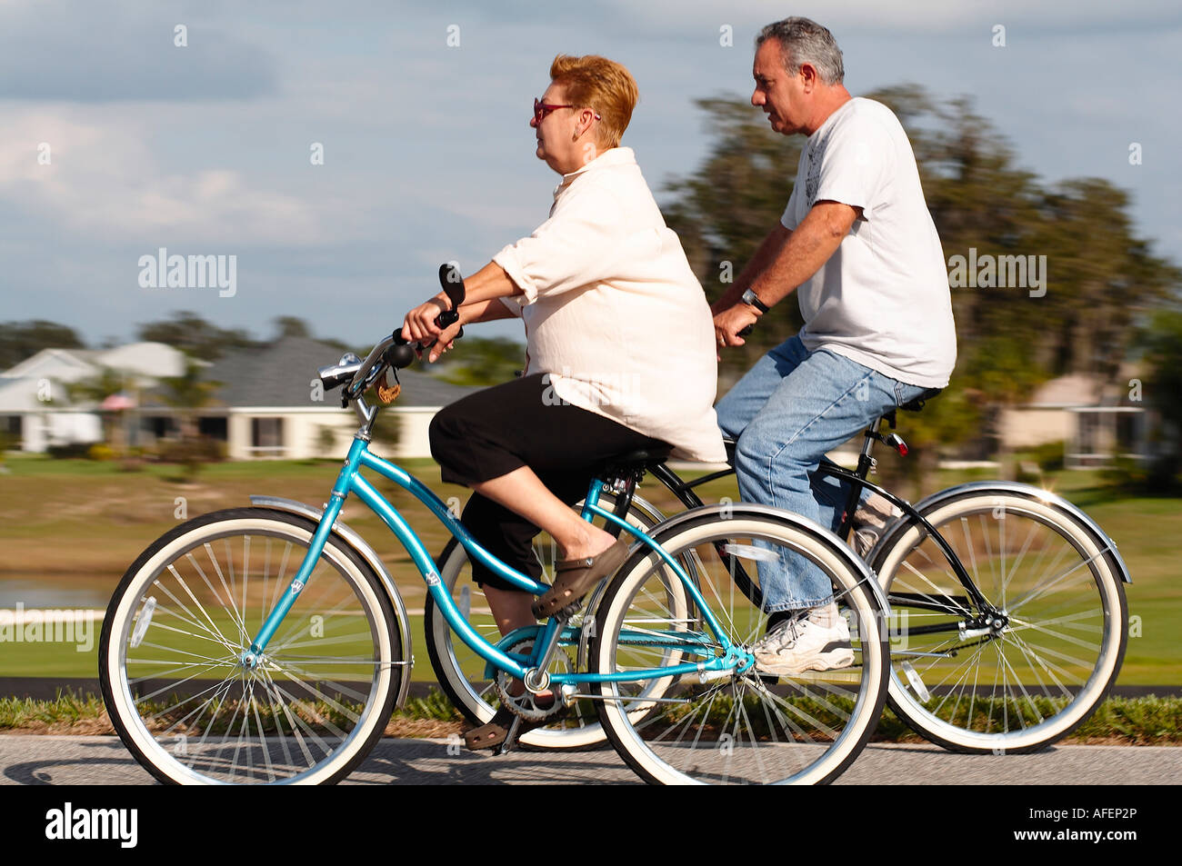 An older couple riding bikes down a sidewalk in Florida Stock Photo Alamy