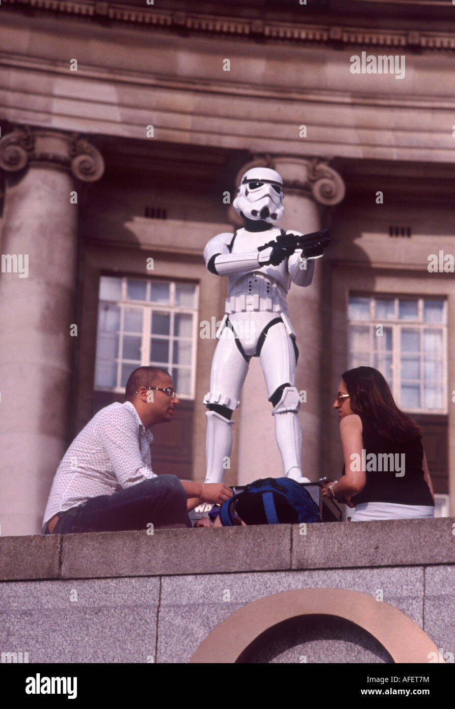 Tourist couple sitting before a Storm Trooper at London County Hall promoting 'Star Wars - The Exhibition' Stock Photo