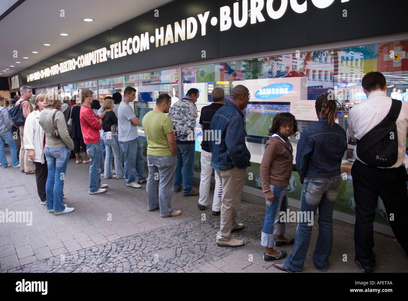 People in Dortmund watching the Brazil v Ghana second round World Cup match in a TV shop window Stock Photo