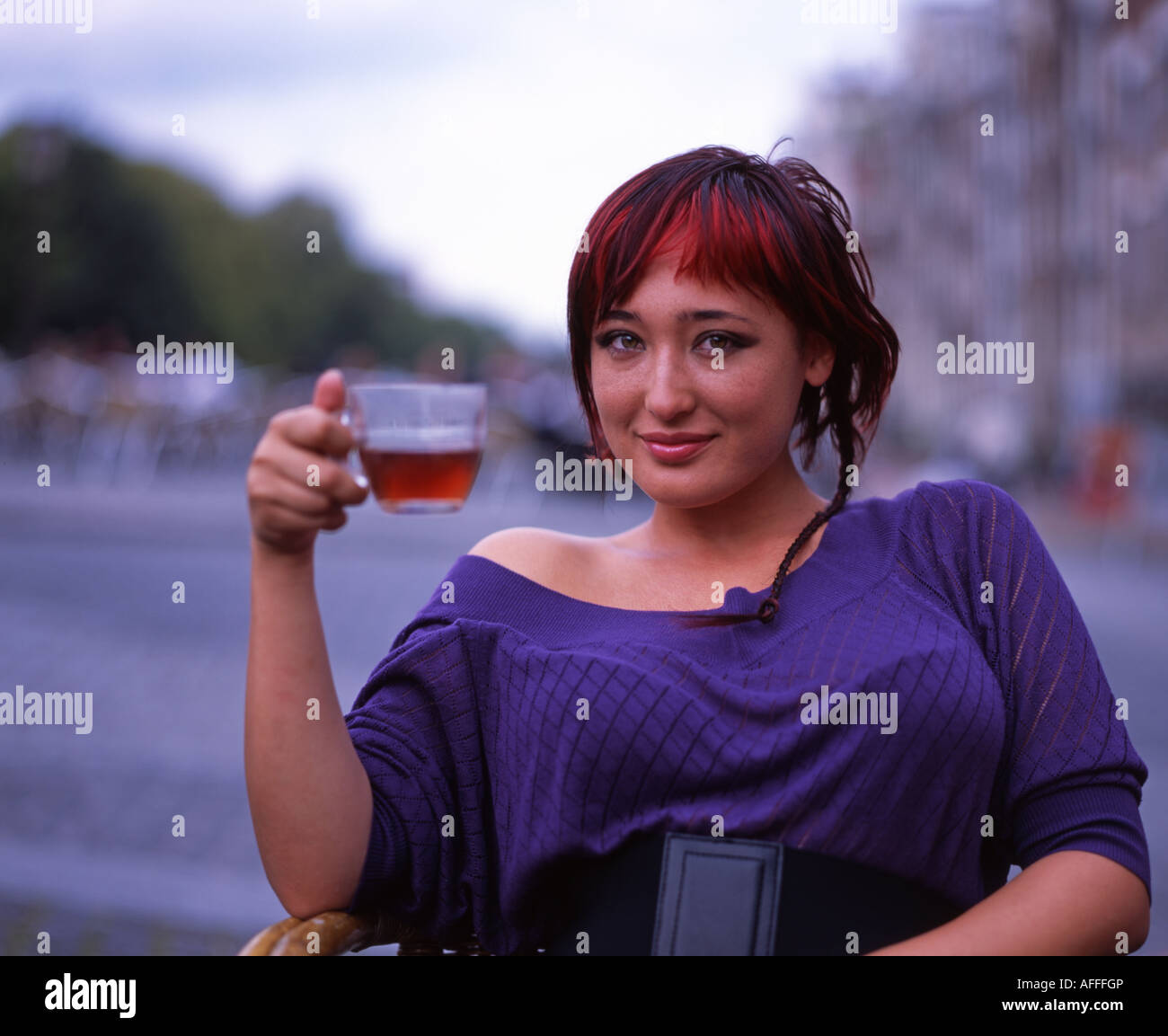 Beautiful Dutch girl sips tea in a cafe beside the canal in central Amsterdam. Stock Photo