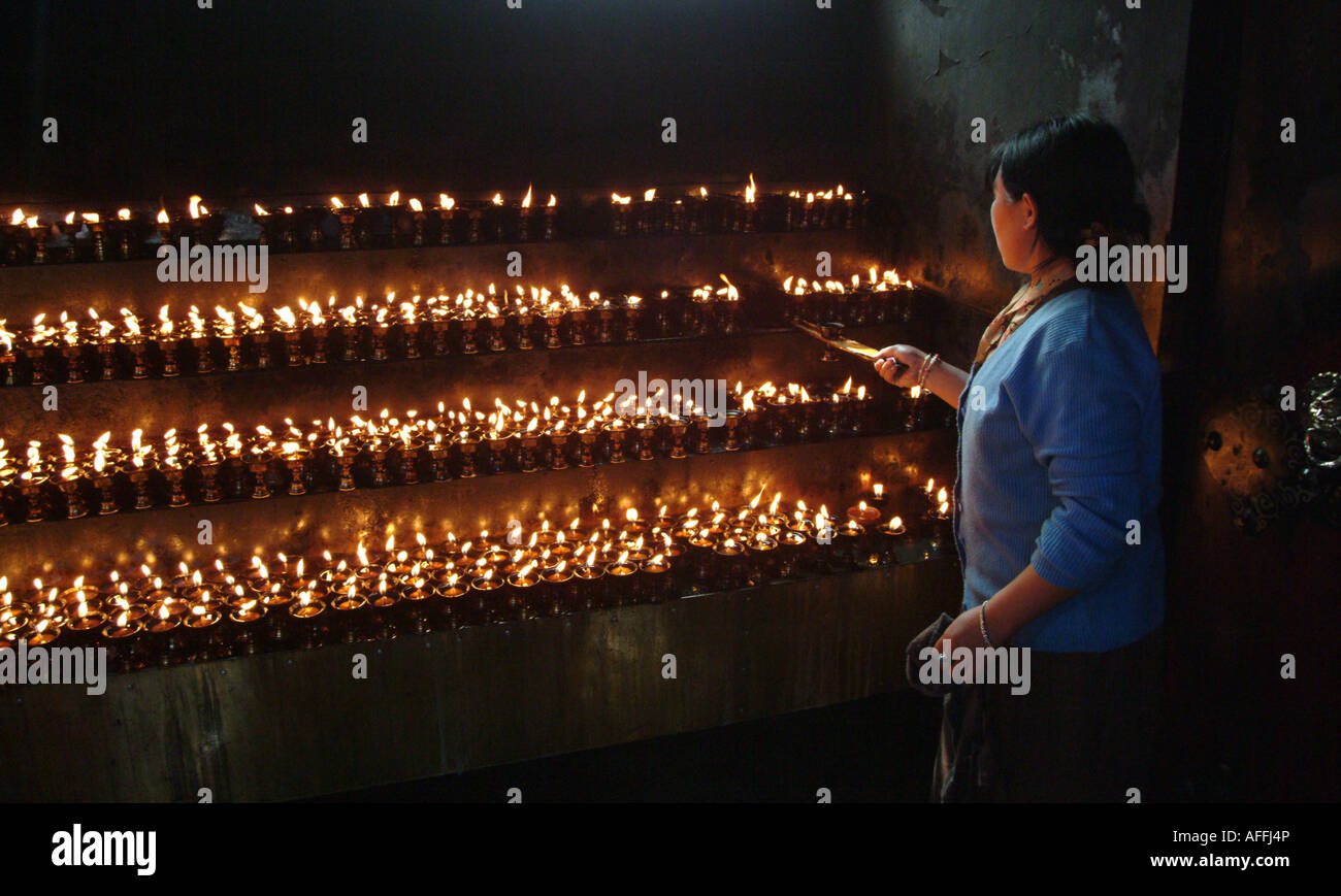 A young Tibetan woman lights butter lights in Lhasa. Stock Photo