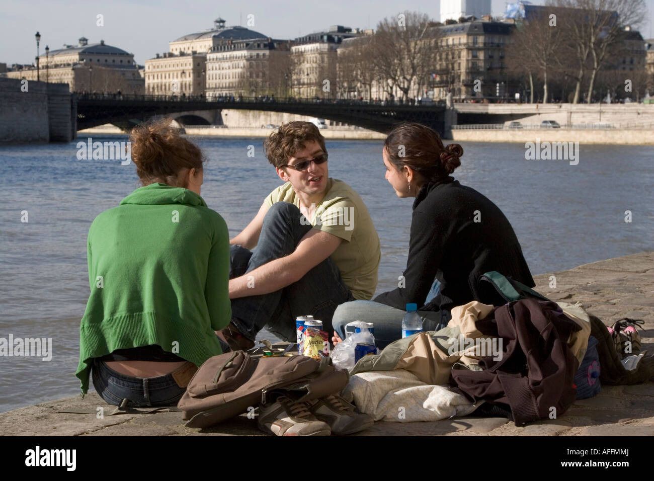 Group of three young Parisians having a picnic by the River Seine in Paris France Stock Photo
