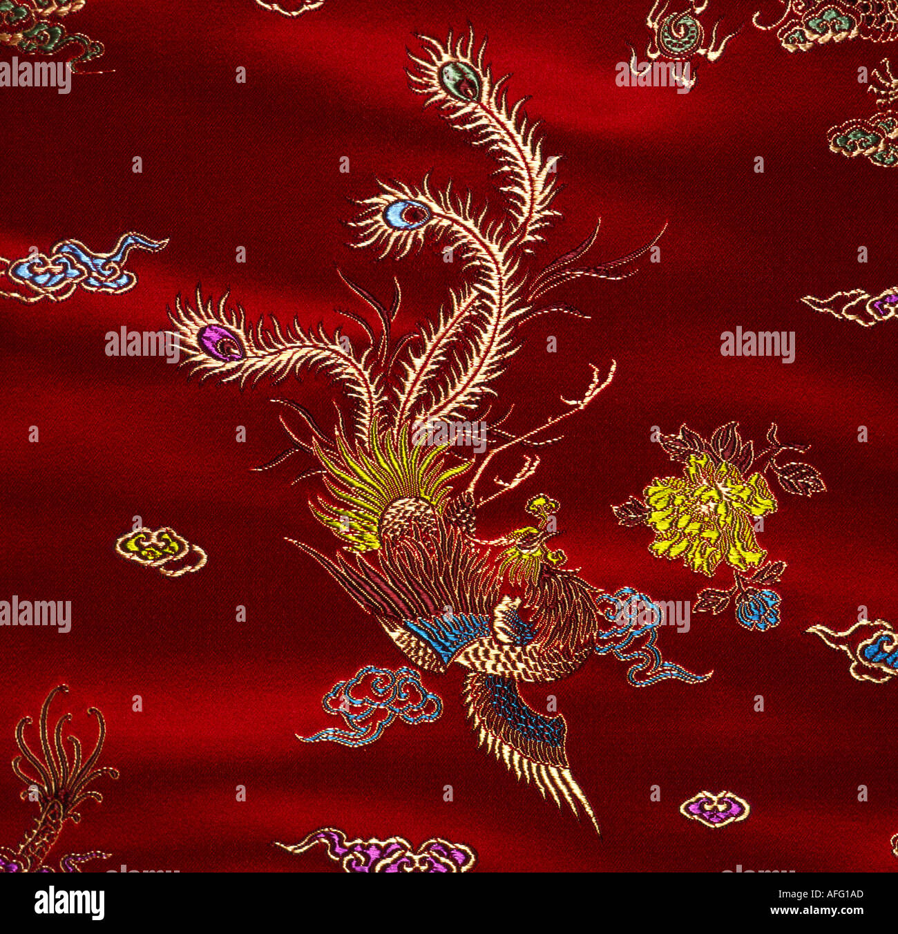 Red silk material textile with peacock embroidery motif Stock Photo