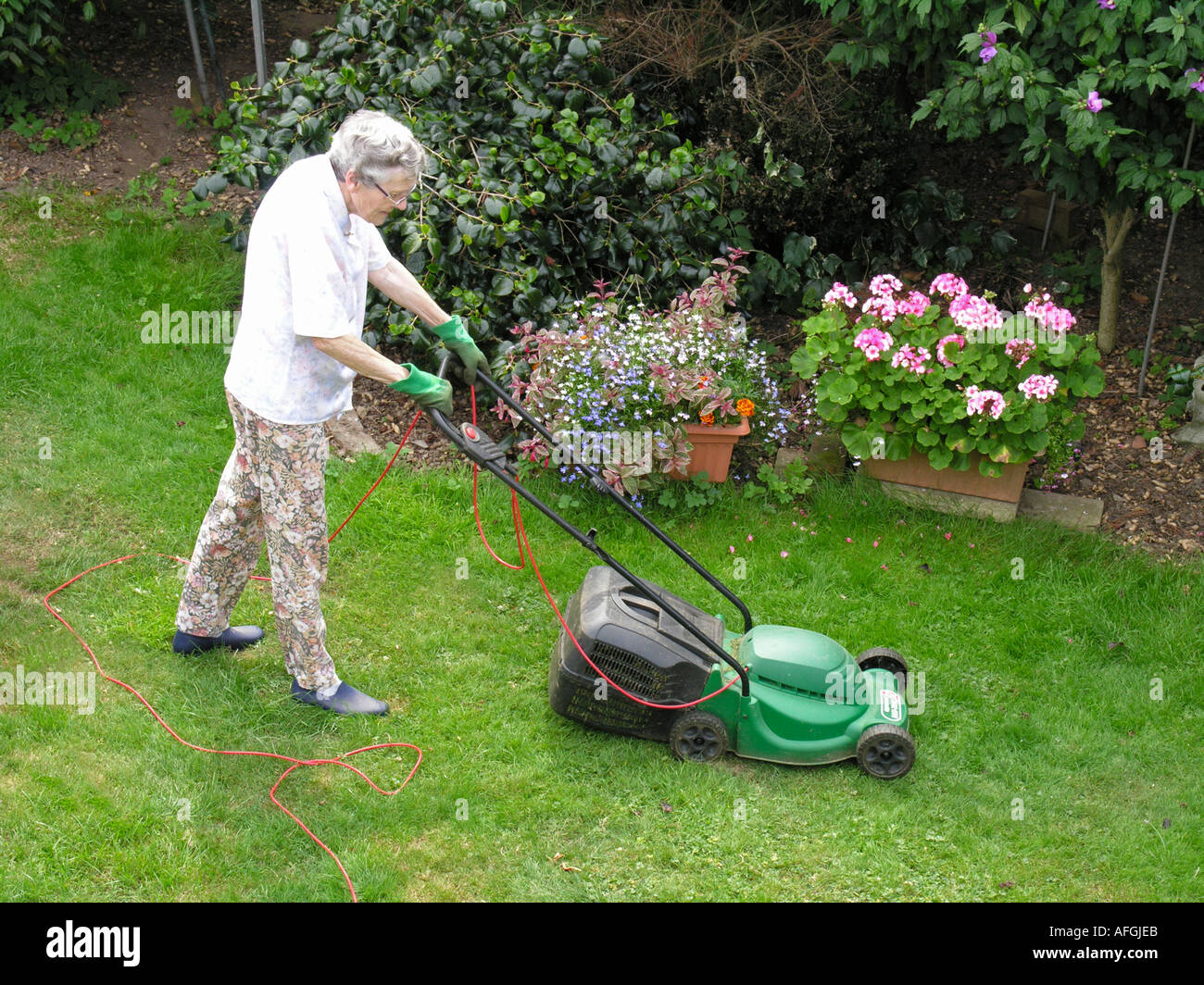 elderly woman mowing the grass Stock Photo Alamy