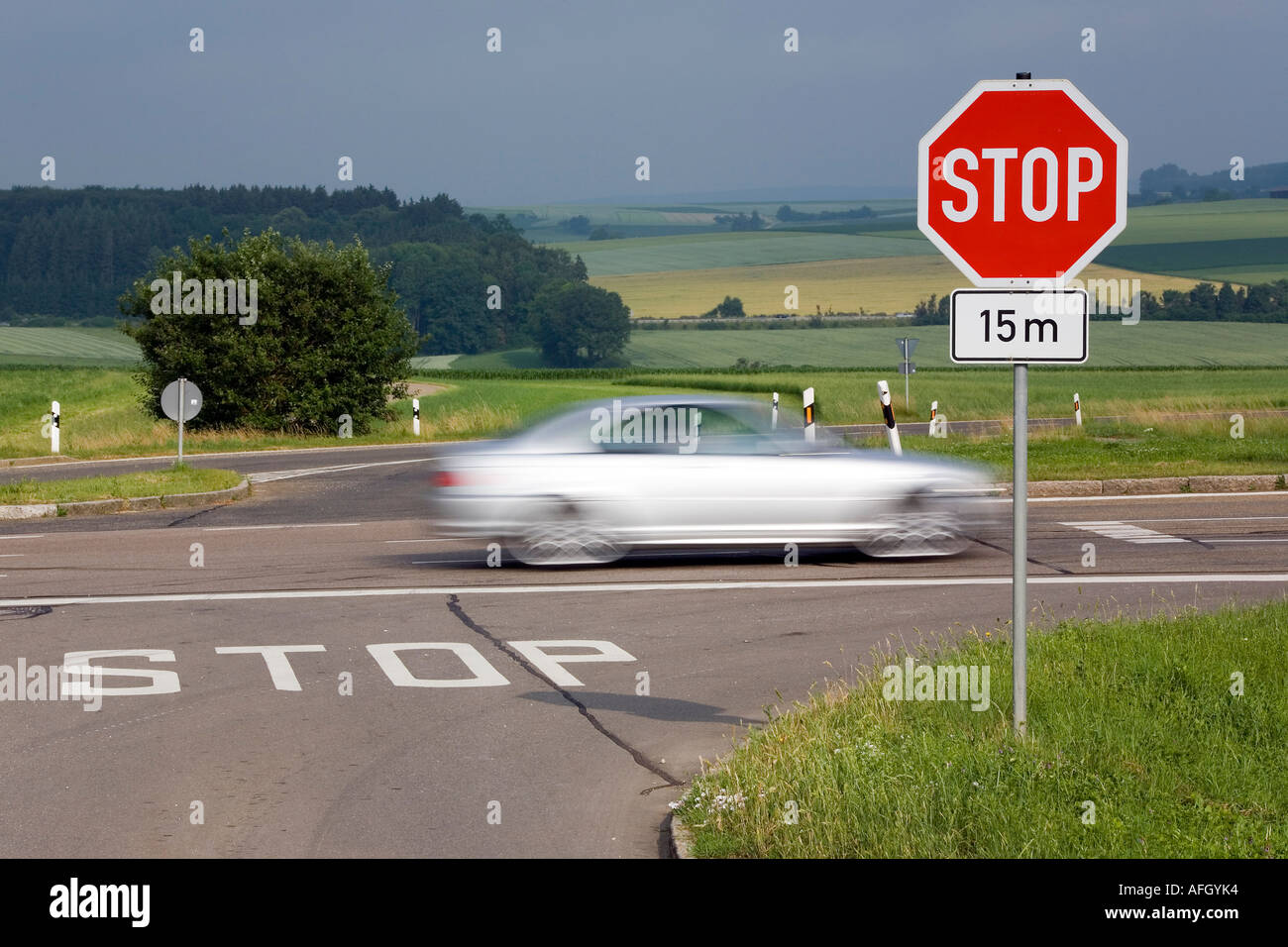 fast car passes a crossroads with a stop sign Stock Photo Alamy