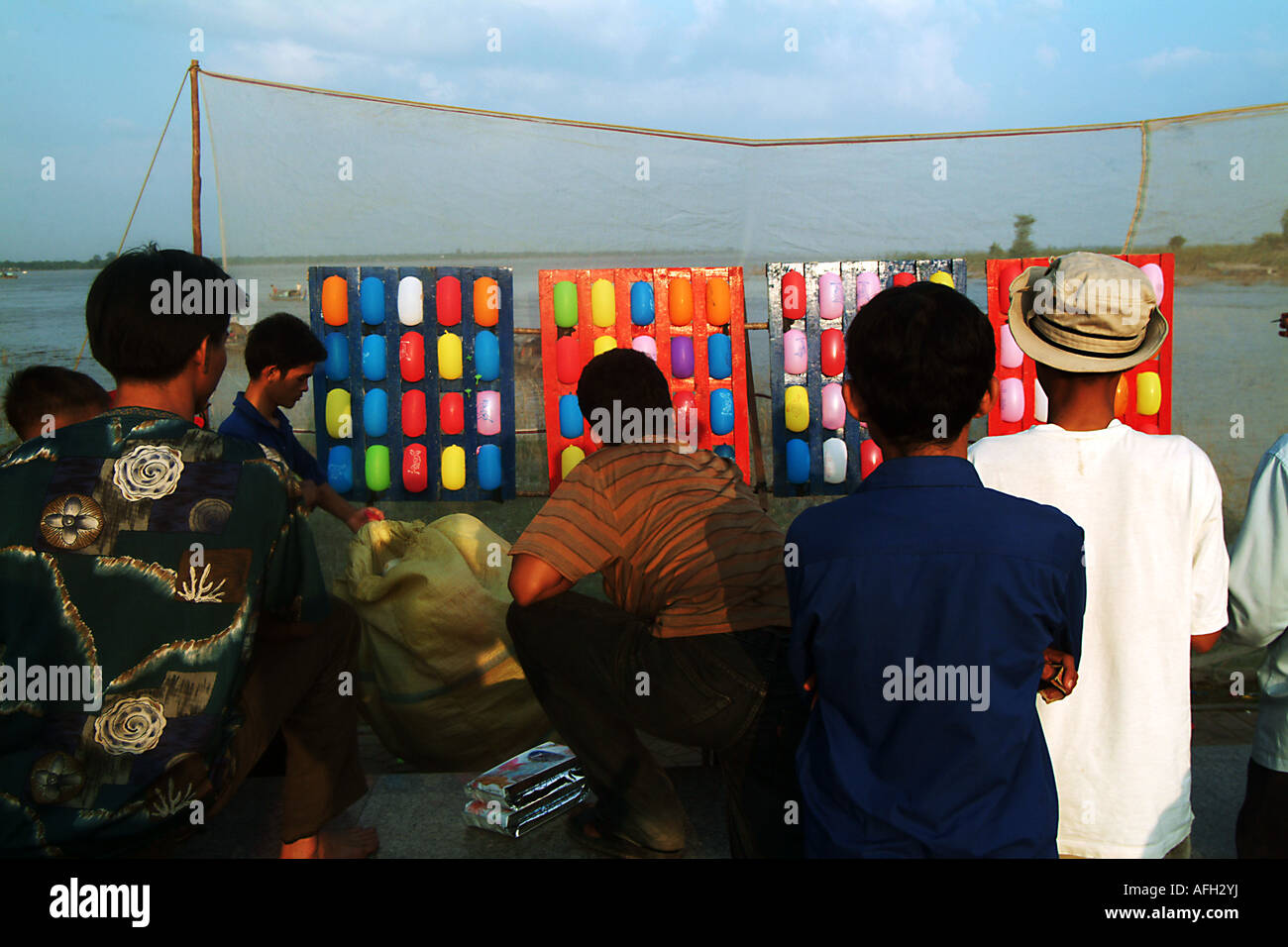 Men throwing darts at balloons at a carnival stall in Pnom Penh Stock