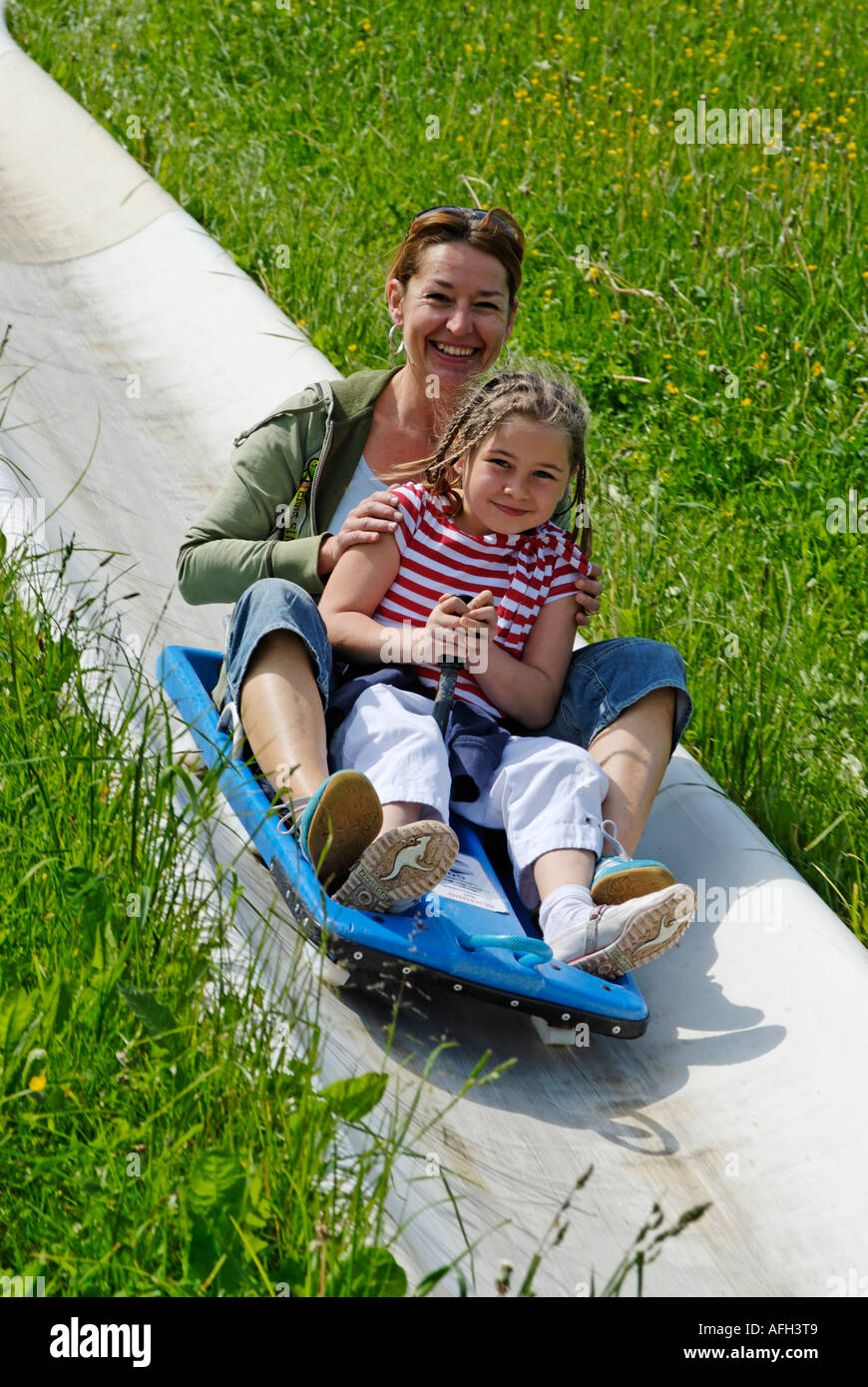 Familiy on a toboggan run in summer sliding with toboggans at the