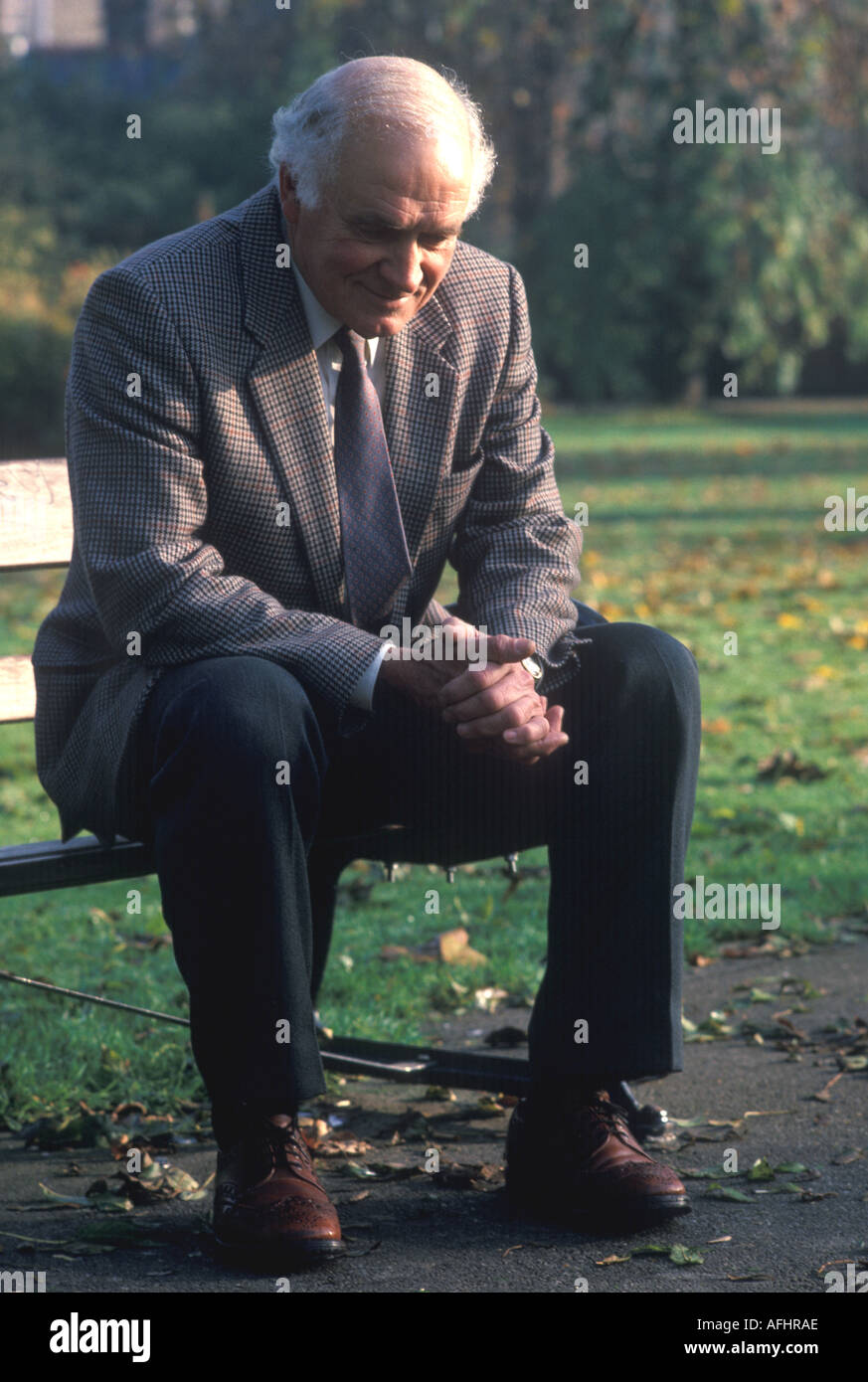 old man sitting on bench in park Stock Photo