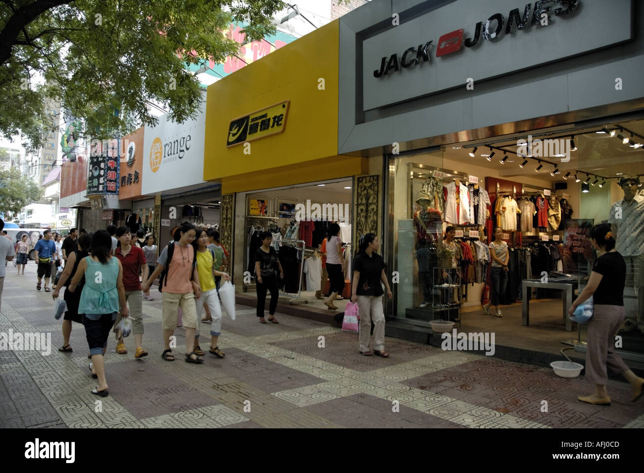 Shoppers walking along the pavement in front of store fronts, Xian, Shaanxi, China. Stock Photo