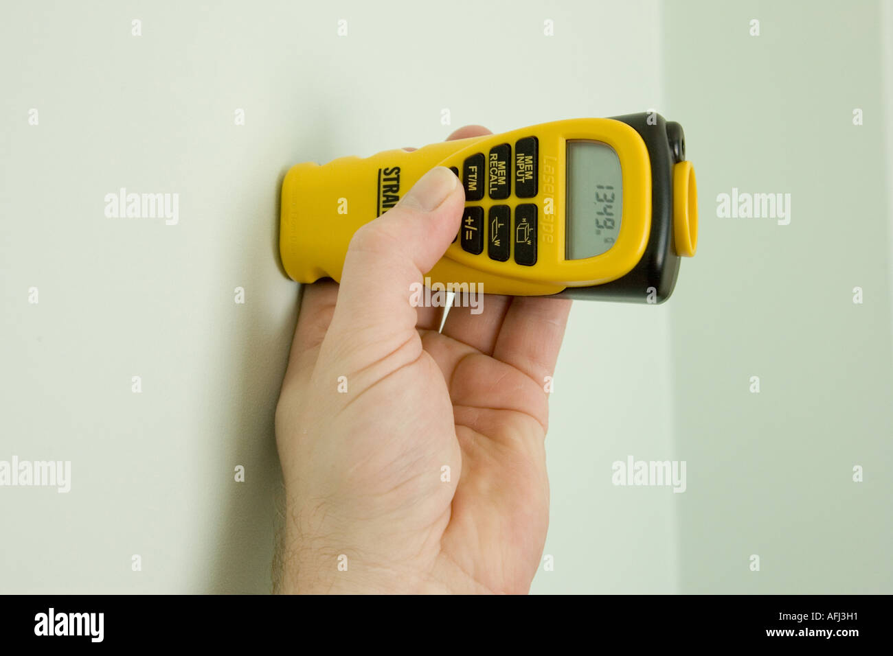 using an ultrasonic measure held against a wall for reference point Stock Photo