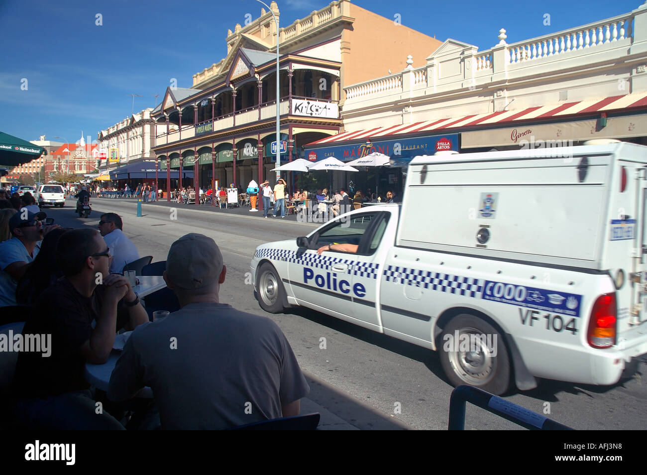 Police van cruises the street between busy outdoor cafes Fremantle Perth Western Australia No PR or MR Stock Photo