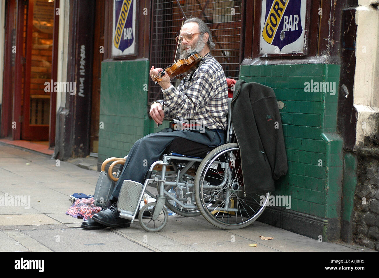 Disabled busker on a wheelchair playing his violin in the streets of