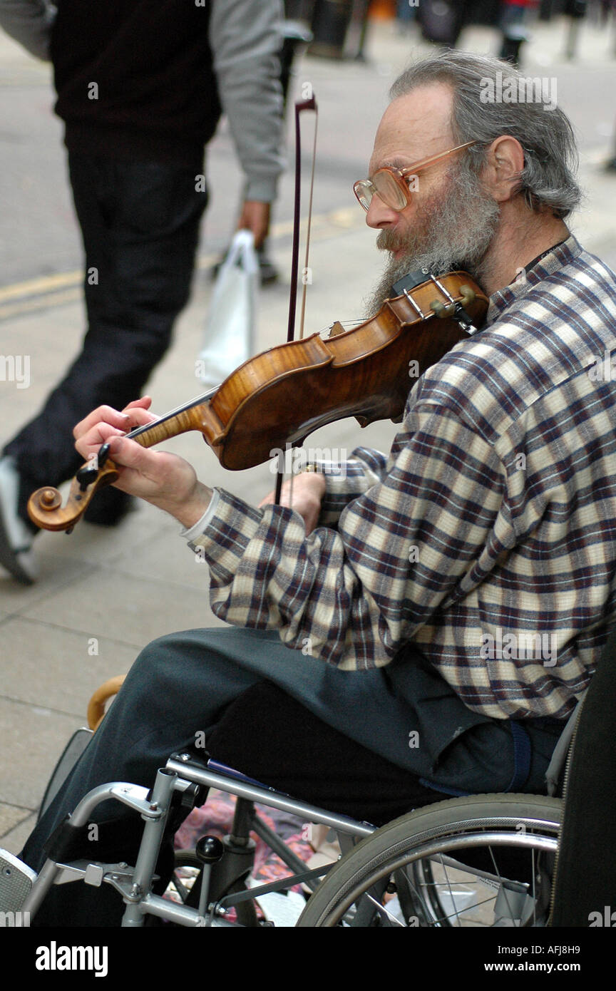 Disabled busker on a wheelchair playing his violin in the streets of