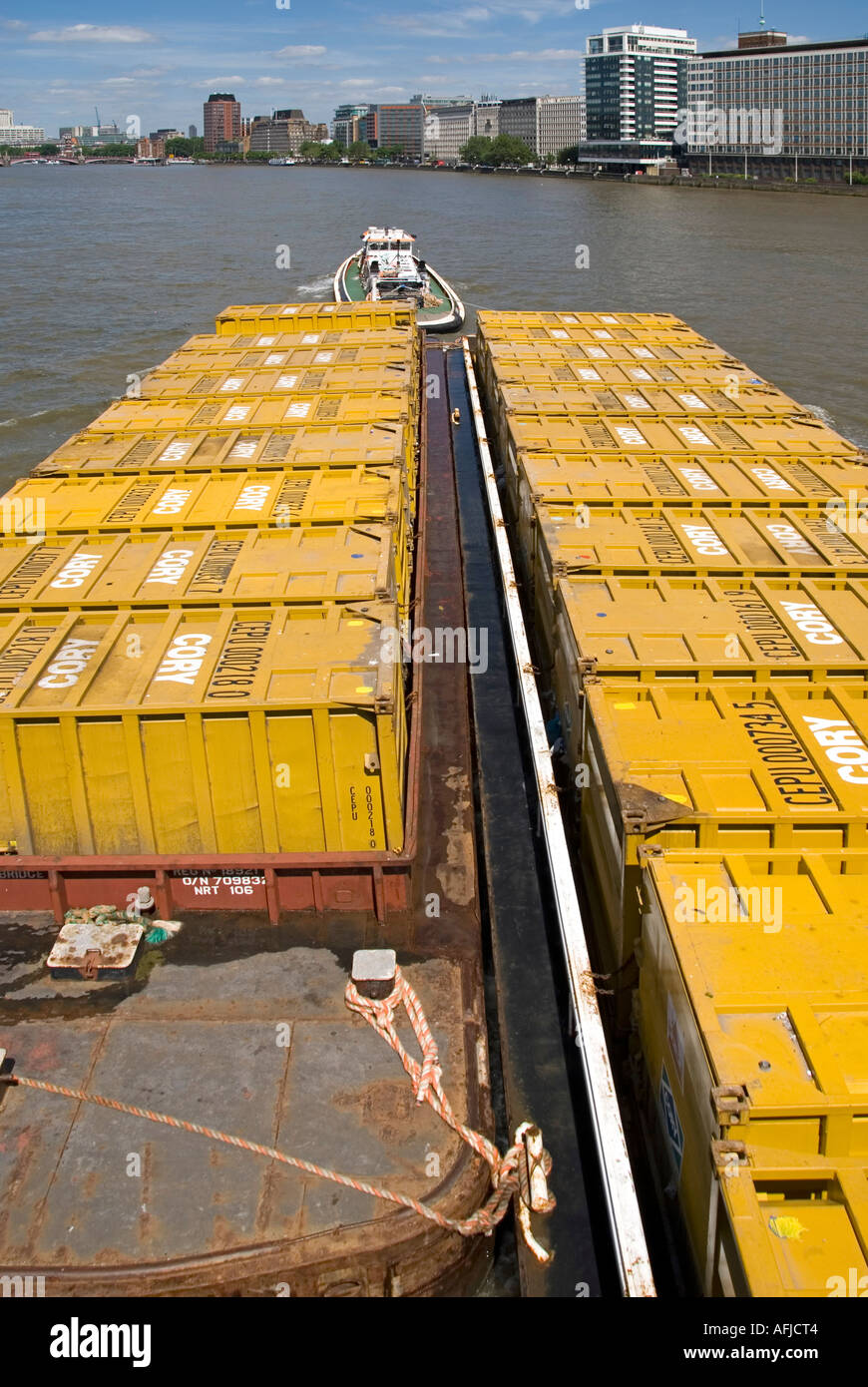 River Thames and Cory waste management company tug towing barges down river loaded with containers full of refuse Stock Photo