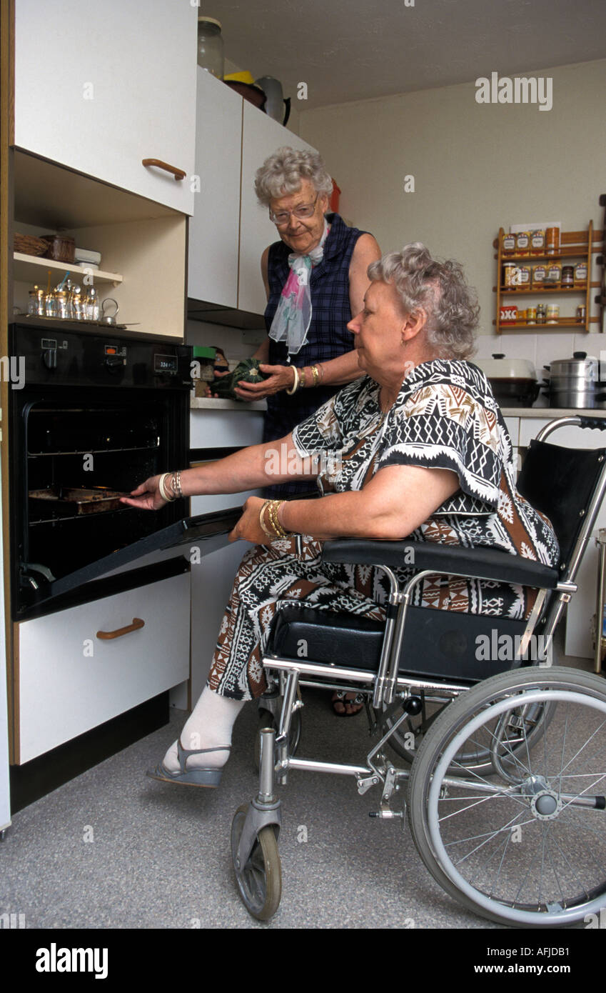 Woman in wheelchair cooking her meal in purpose built accommodation with  low level oven Stock Photo - Alamy