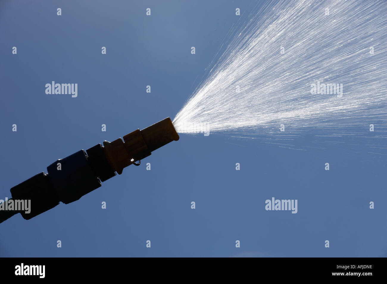 JET OF WATER SPRAYING FROM GARDEN HOSE PIPE IN SUMMER SUN Stock Photo
