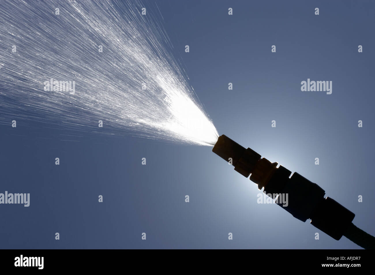 JET OF WATER SPRAYING FROM GARDEN HOSE PIPE IN SUMMER SUN Stock Photo