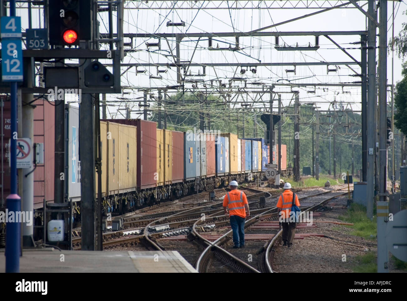 Railway tracks shipping container train and two rail workers in high ...