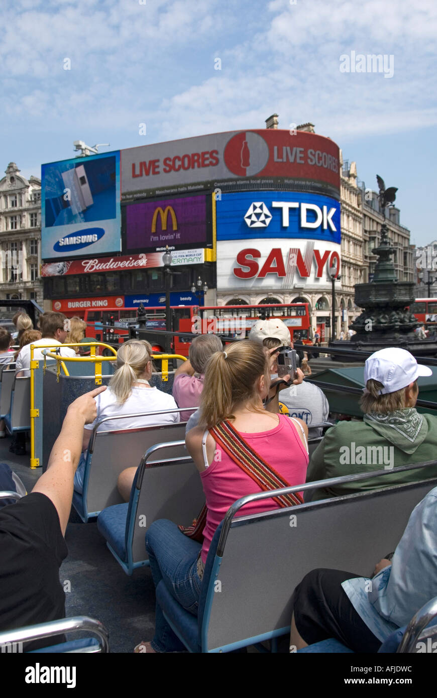 London passengers onboard top deck of open top sightseeing tour bus with tourists views towards Piccadilly Circus & Eros with advertising hoarding UK Stock Photo