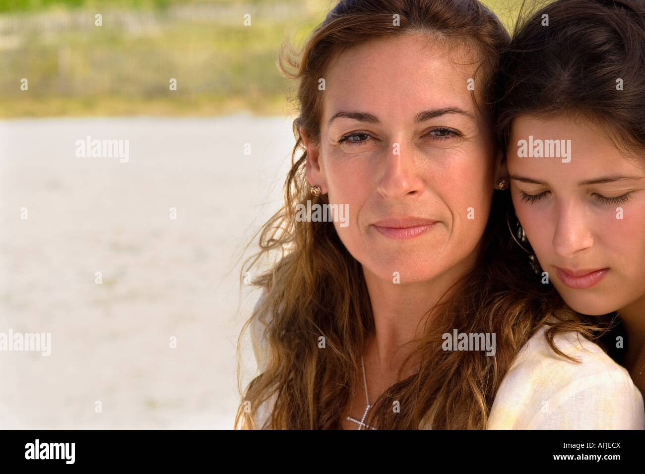 Two women sitting side by side at beach Stock Photo - Alamy