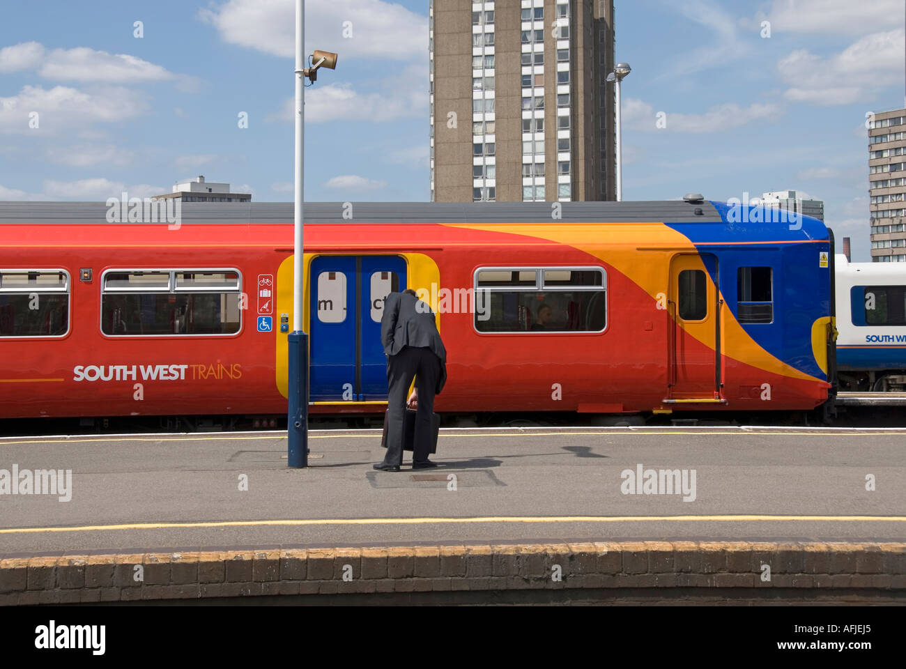 Clapham Junction railway station with gentleman wearing formal business suit waiting on platform as South West Train arrives South London England UK Stock Photo