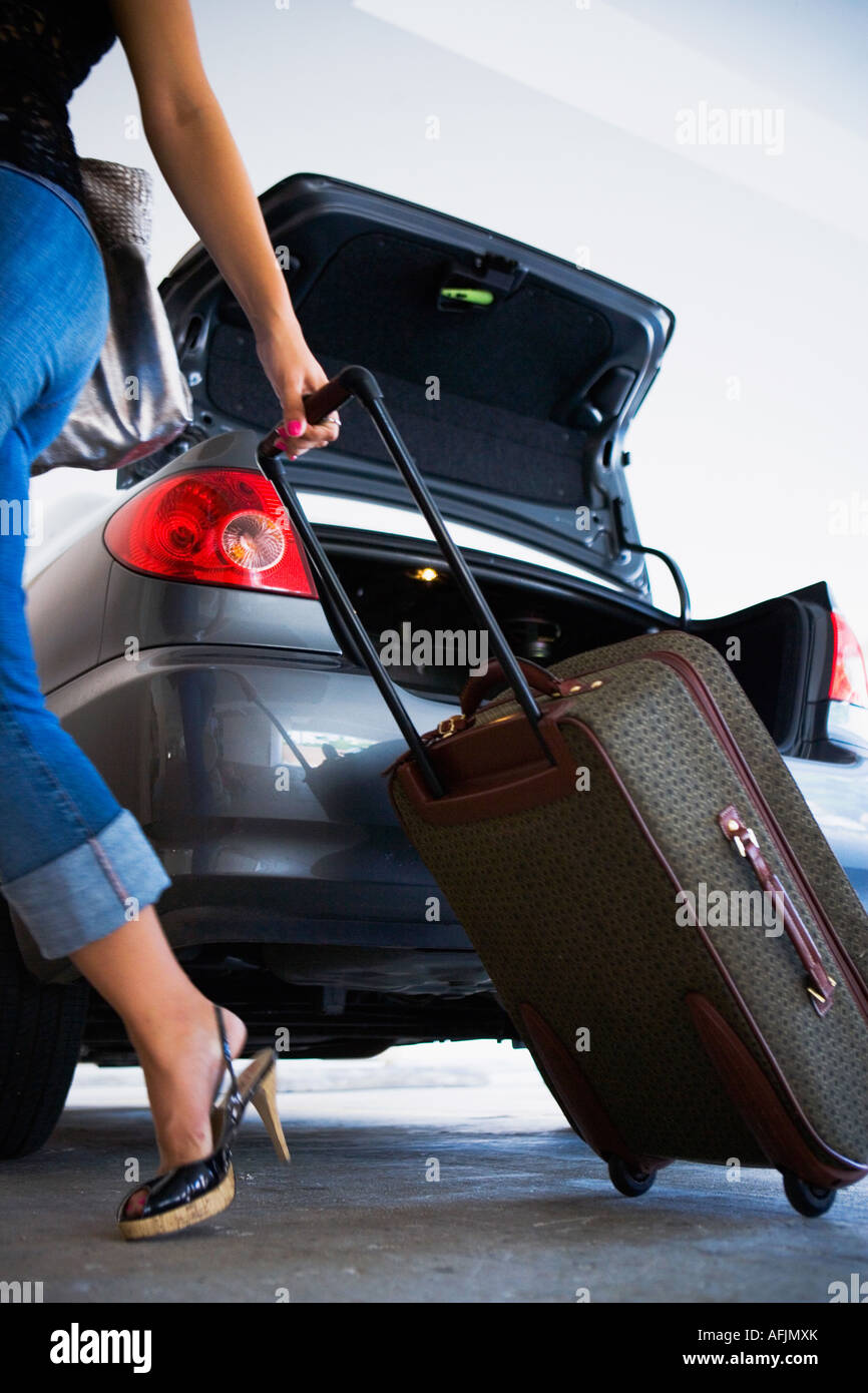 Young woman unloading luggage from car Stock Photo - Alamy