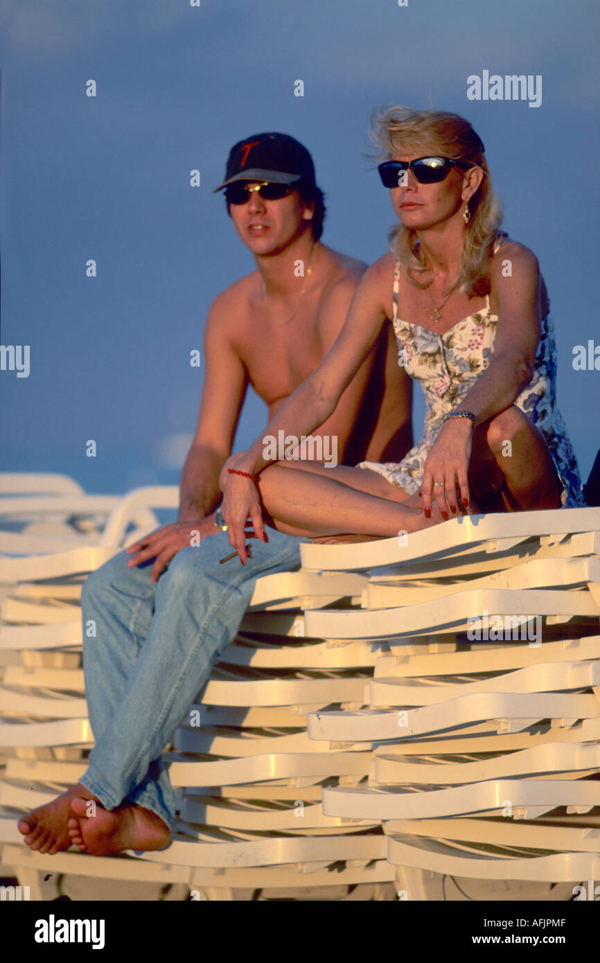 Couple sitting on stack of sun loungers Miami Beach USA Stock Photo