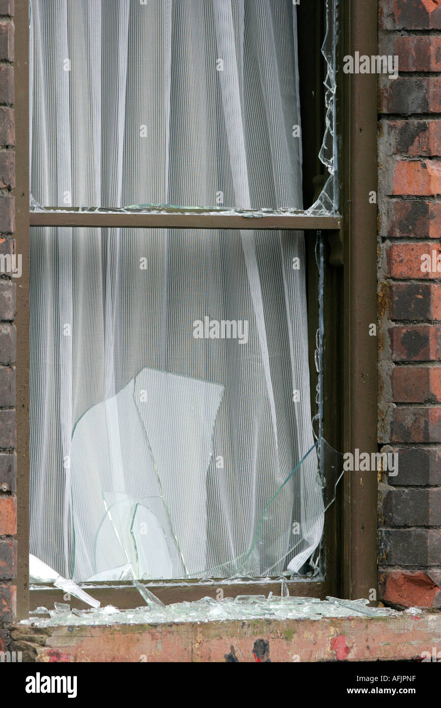 remains of bombed out window with net curtains and broken glass in building on set of the movie Closing the Ring based in Belfas Stock Photo