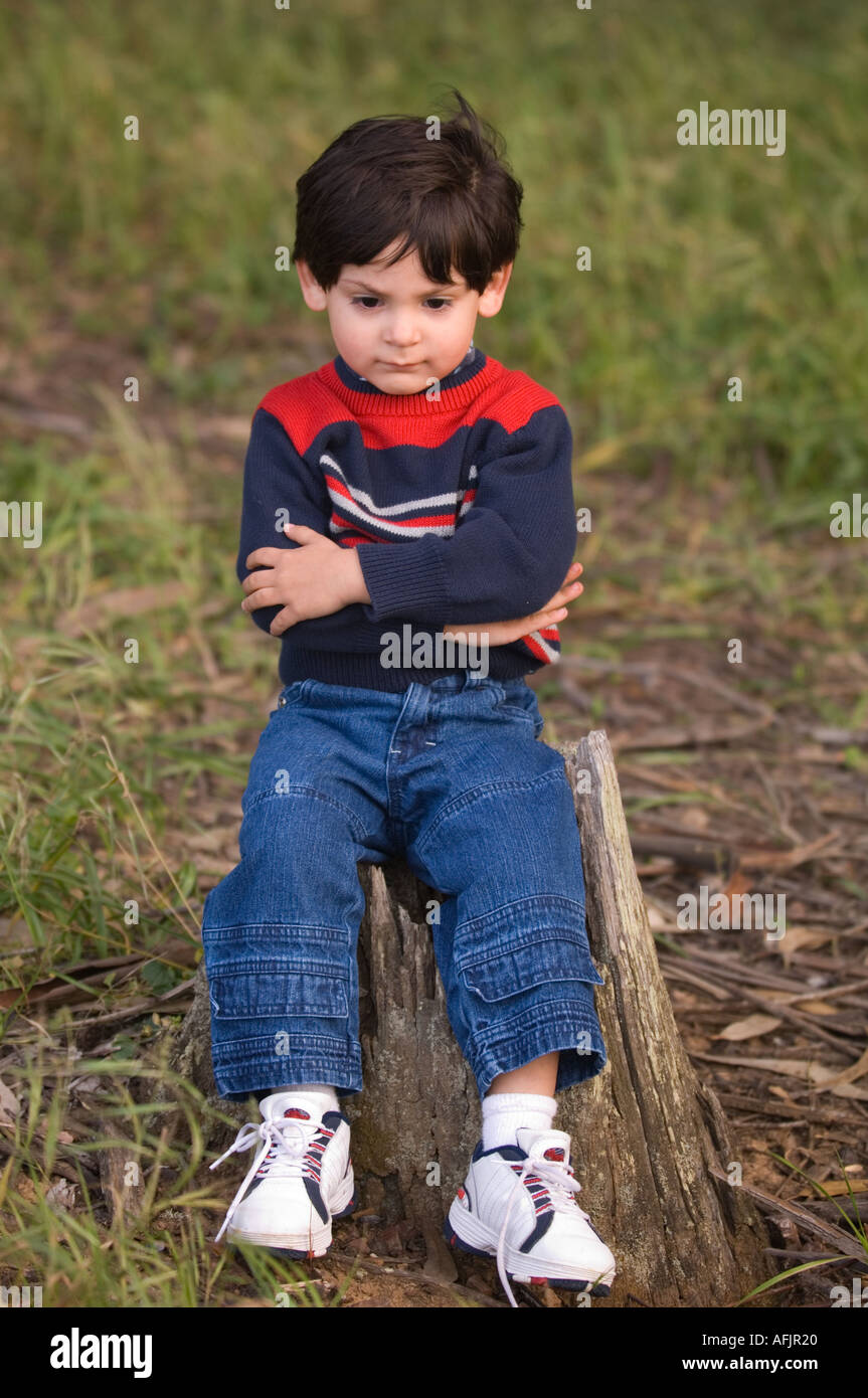 small boy with brown hair and a striped sweater jeans and sneakers