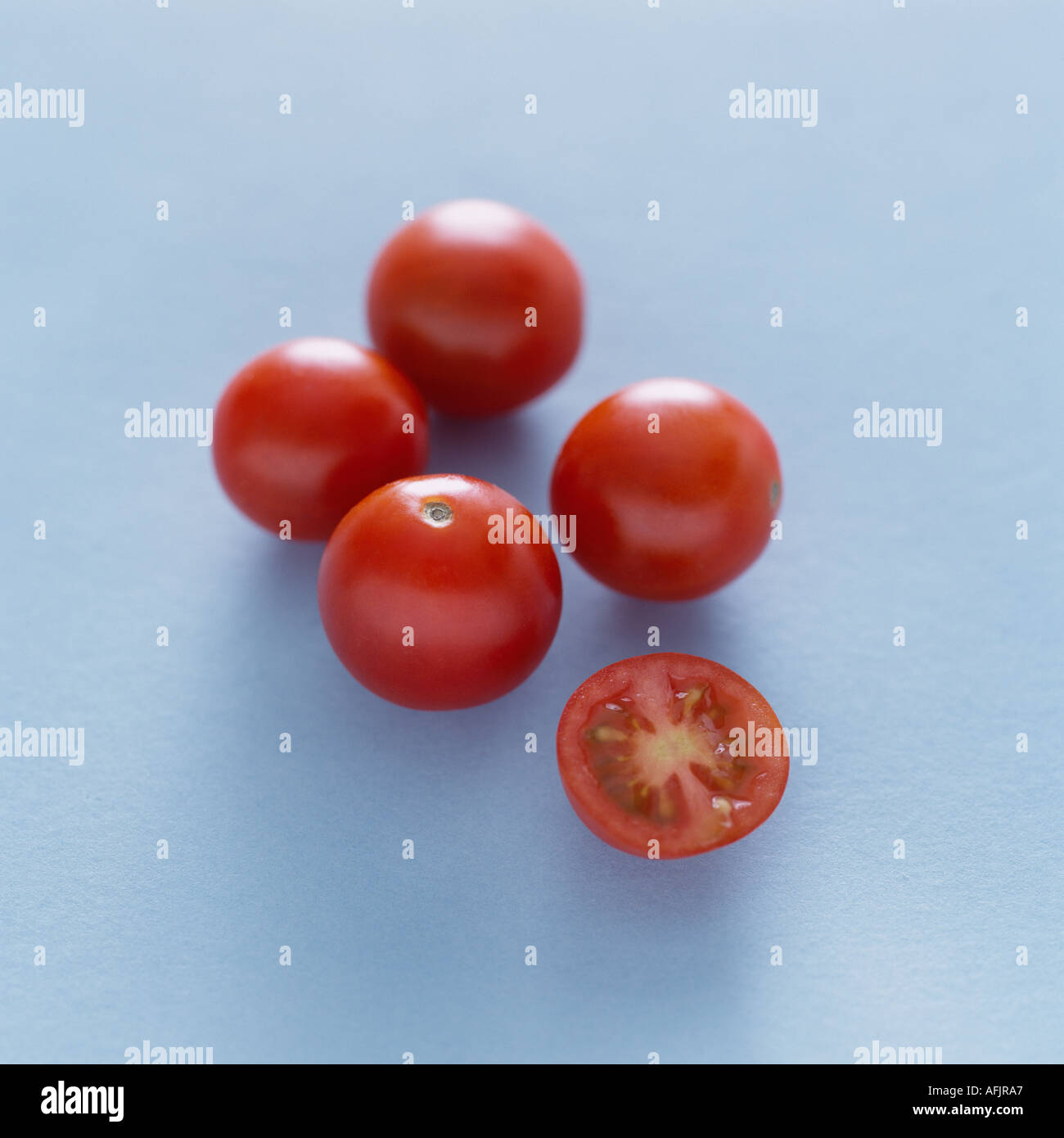Five cherry tomatoes on a pale blue background Stock Photo