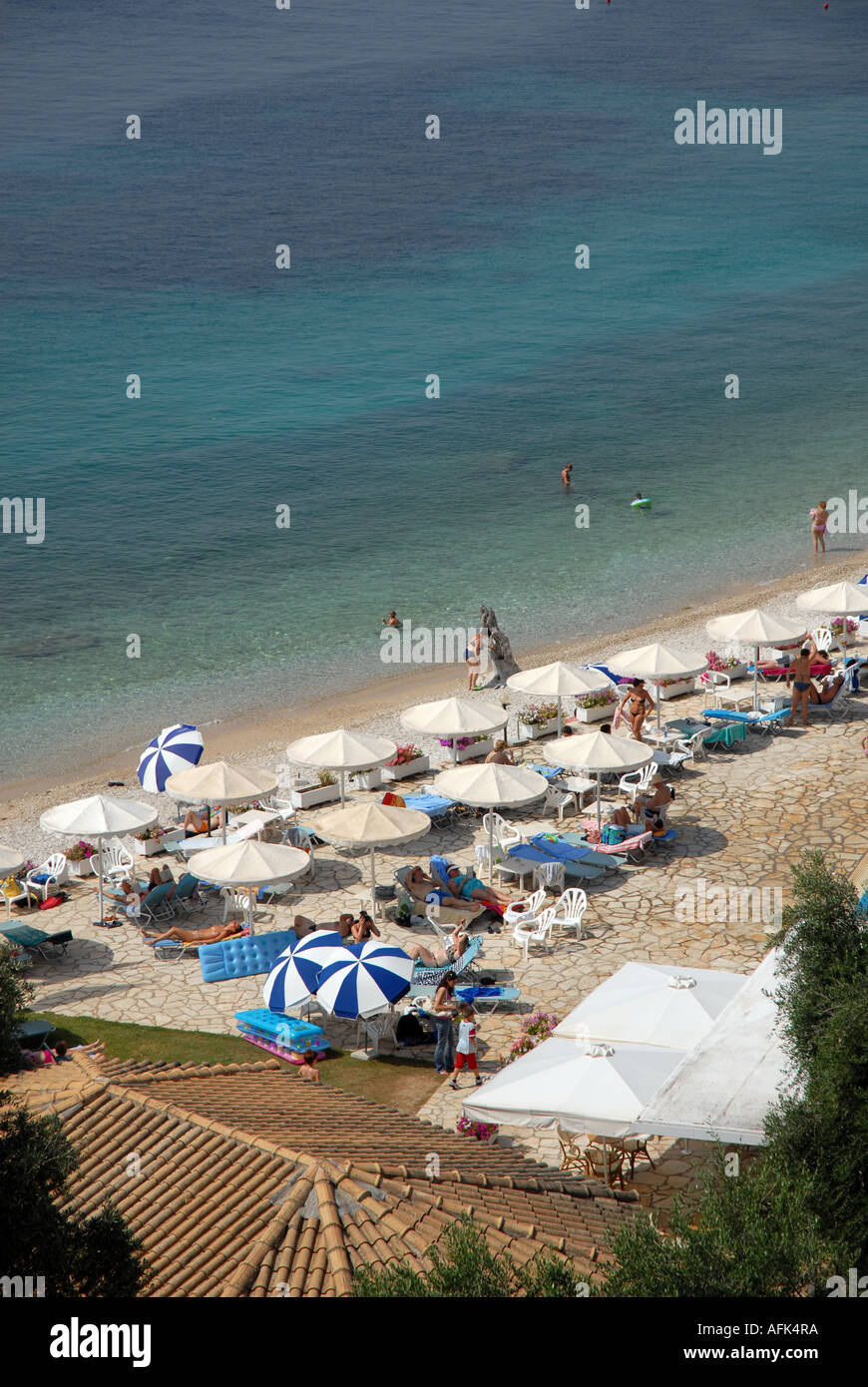 High view of pool-side umbrellas, beach and sea, Nissaki Beach, Corfu, Greece with people sun bathing and swimming Stock Photo