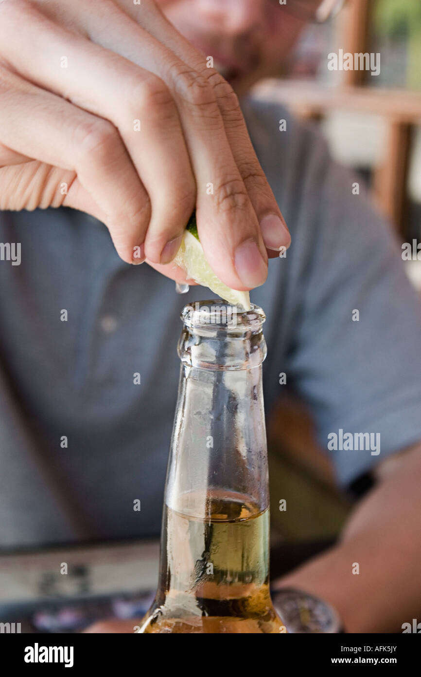 Close-up of man squeezing lime into beer. Stock Photo