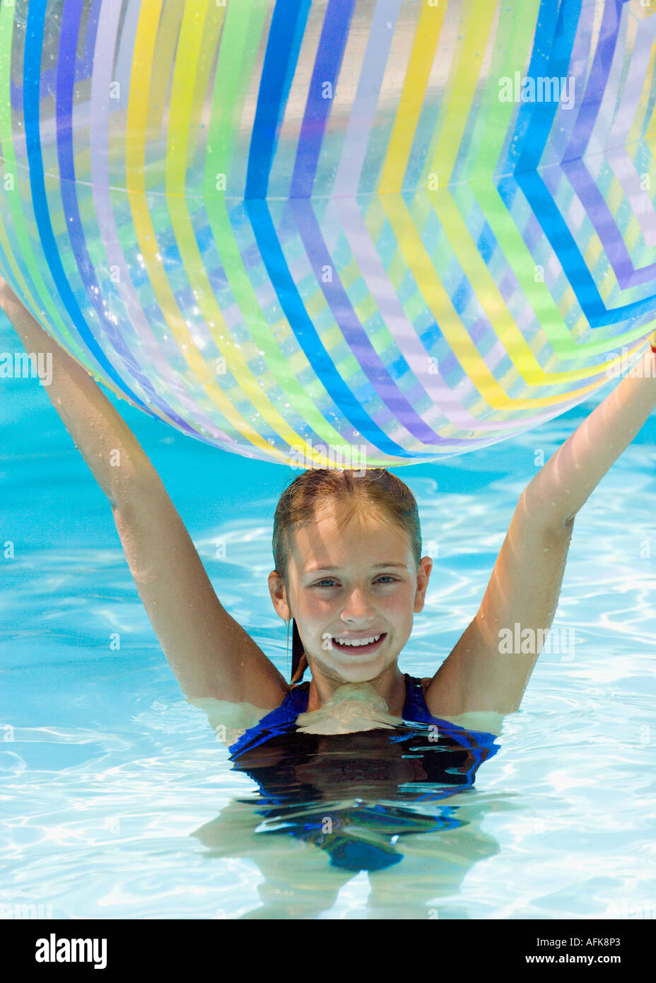 Girl holding beach ball over head in swimming pool Stock Photo