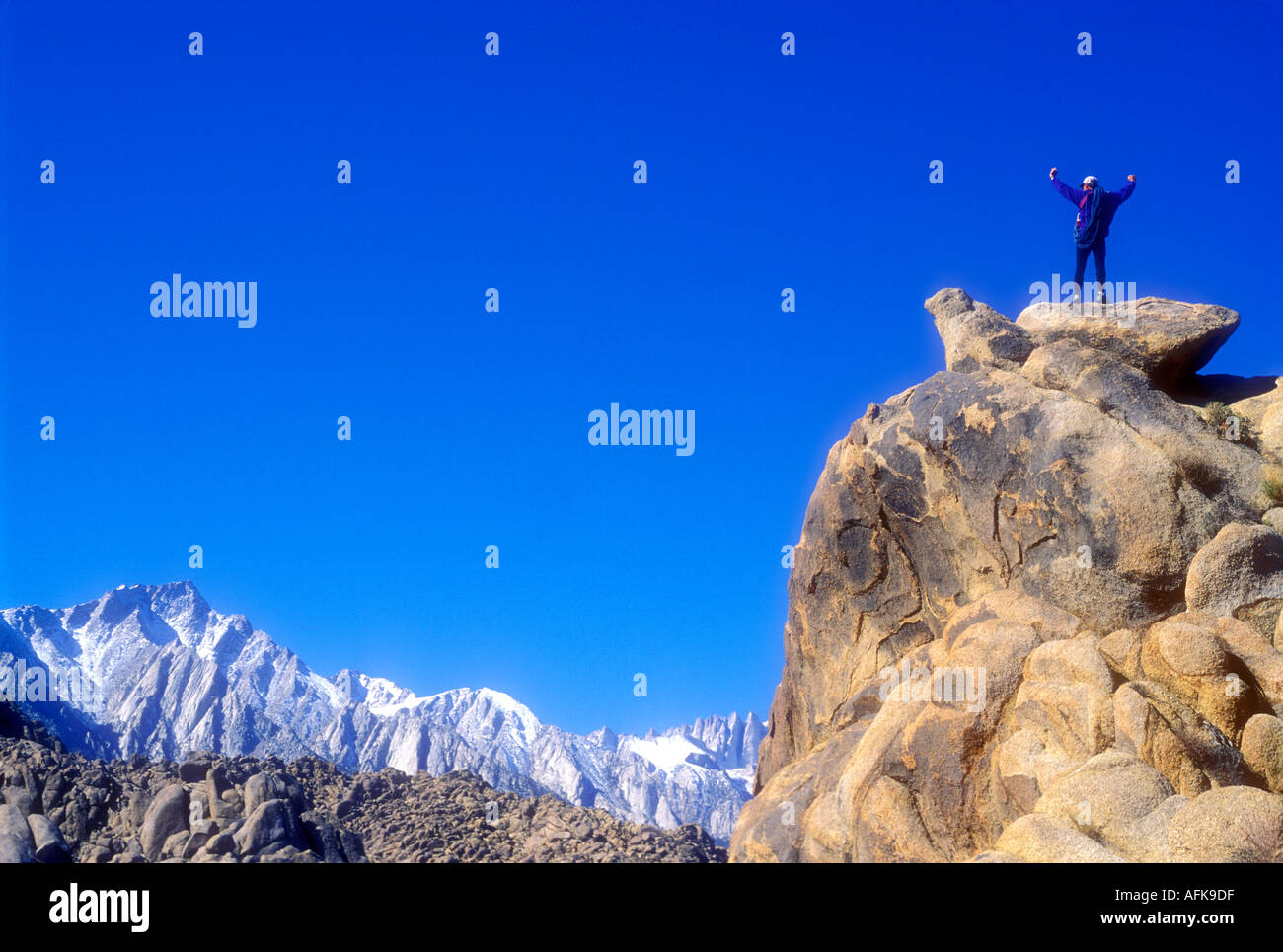 Climber on top of rock summit with arms raised Model Released Photo Stock Photo