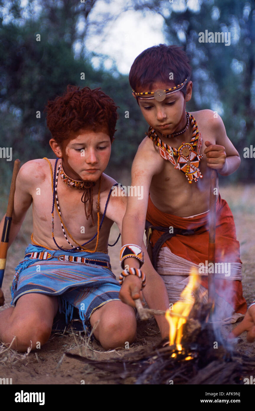 Children dressed as Samburu warriors 'make' fire on a Cheli & Peacock family mobile safari. Stock Photo