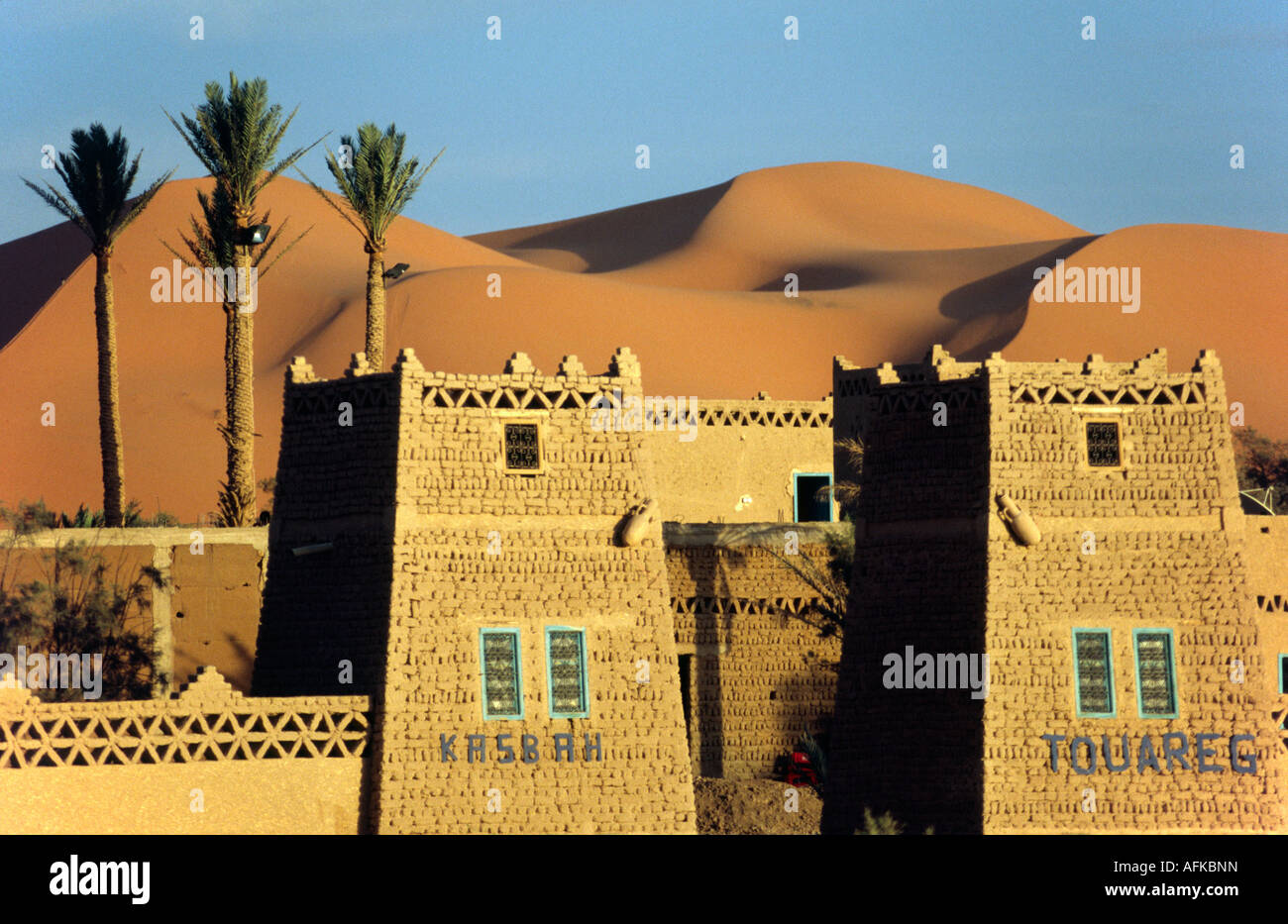 A desert kasbah backing onto the giant sand dunes of Erg Chebbi in eastern Morocco.   Stock Photo