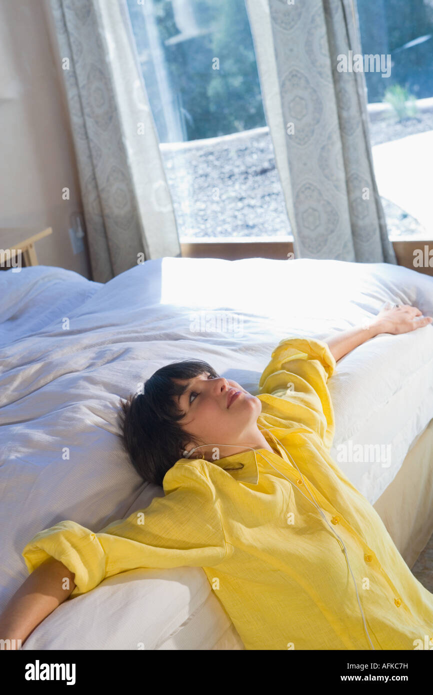 Woman leaning on bed listening to music Stock Photo Alamy