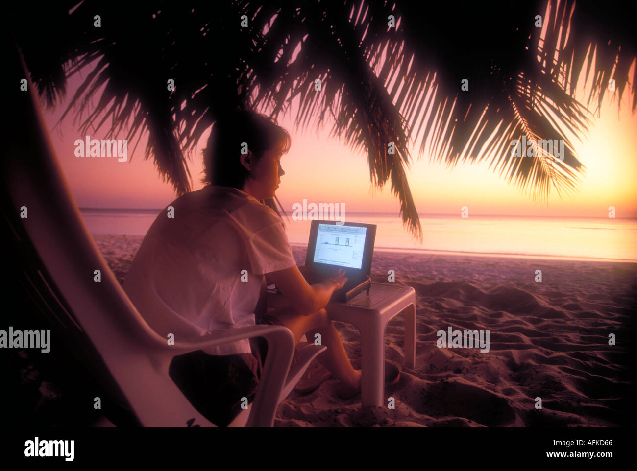 Woman working on laptop computer on beach in Maldives Indian Ocean Model Released Image Stock Photo