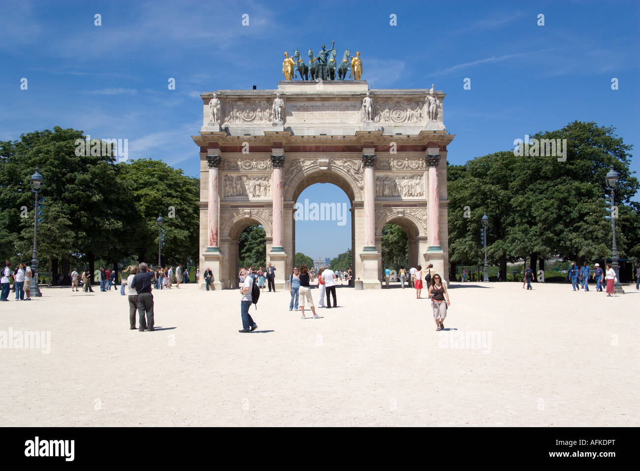 FRANCE Ile de France Paris People walking from Jardin des Tuileries through Arc de Triomphe du Carrousel towards Louvre Museum Stock Photo