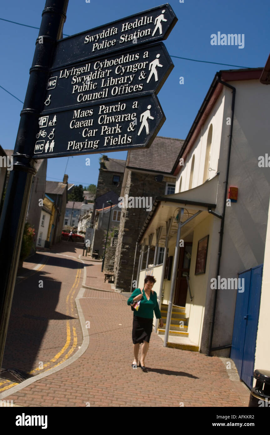 bilingual welsh english street signs and woman walking in the sun Llandysul Ceredigion Wales Cymru Stock Photo