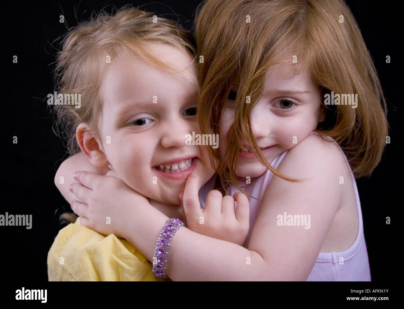 Two little girls hugging with a kiss from the big sister Stock Photo