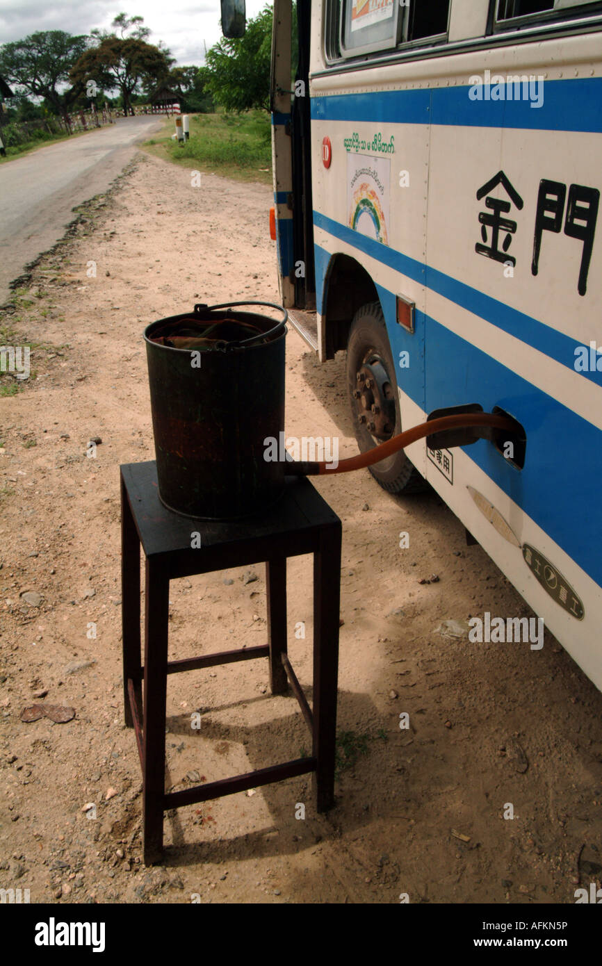 A Chinese bus in Burma fills up with fuel at a roadside filling station. Stock Photo