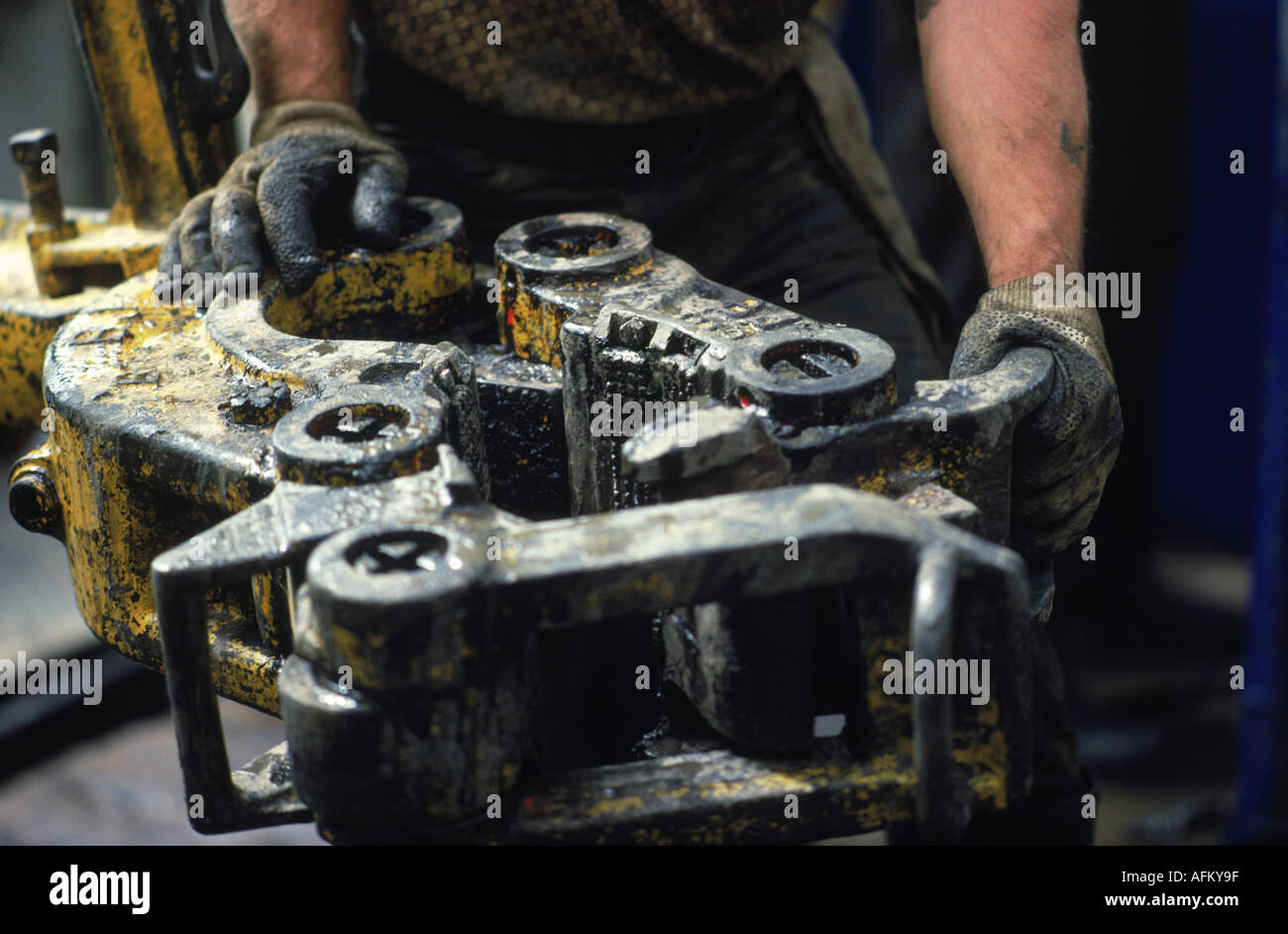 Hands holding drilling bit on offshore oil derrick Stock Photo