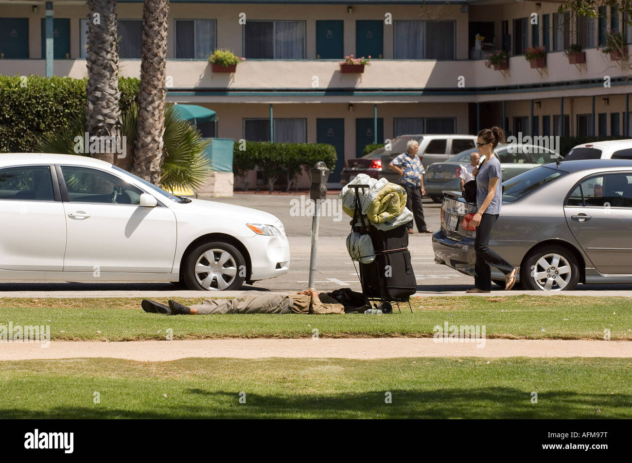 A man lies on the grass in Santa Monica California where the homeless are known to frequently stay Stock Photo