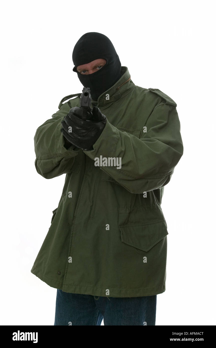 Armed man in a balaclava aiming a handgun at his target Stock Photo