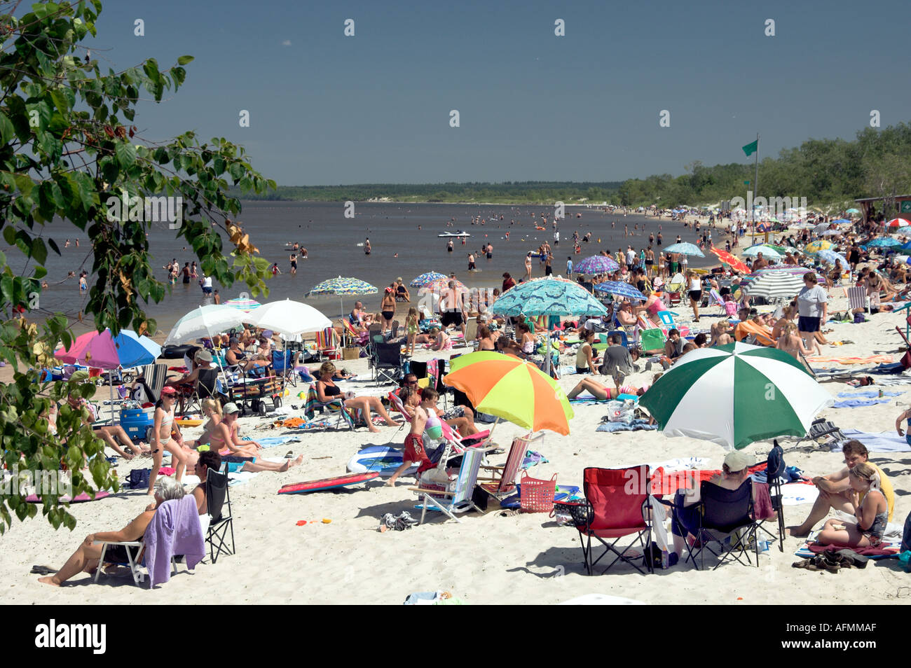 Beach scene with sunbathers and colorful umbrellas at Grand Beach Provincial Park on Lake Winnipeg Manitoba Canada Stock Photo