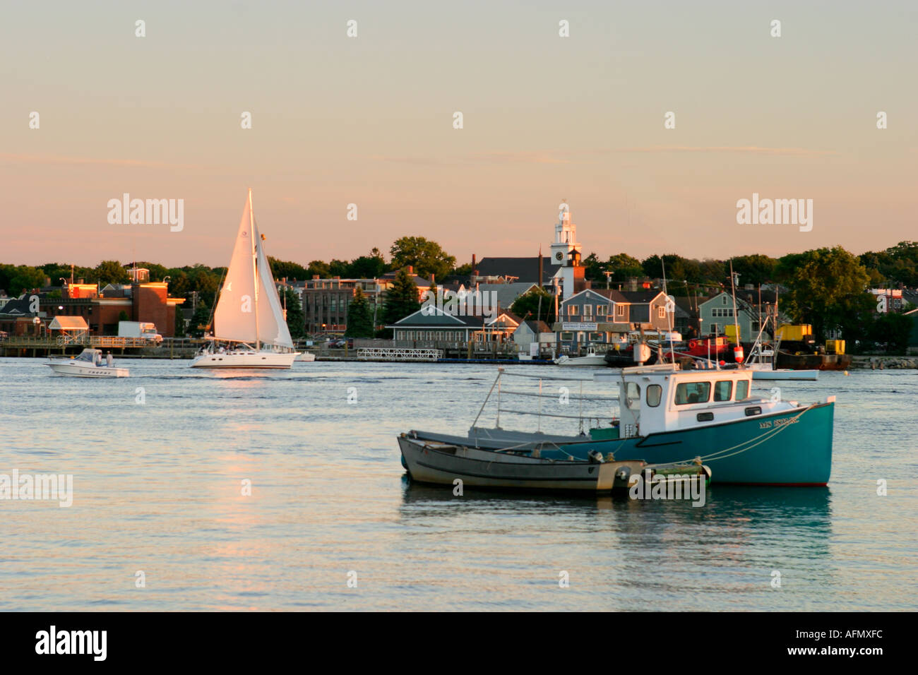 A sailboat and fishing boat share Newburyport MA harbor as the sun sets
